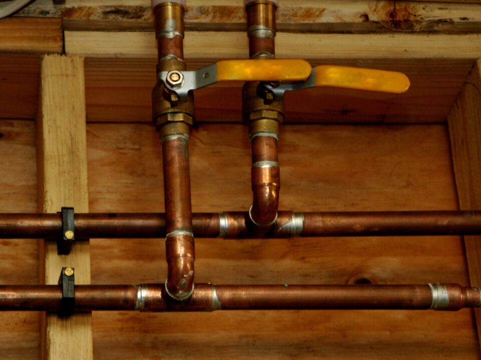a top-down view of several aging copper pipes that are part of a residential plumbing system